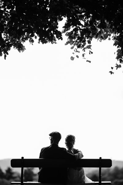 夫妇俩坐在树下的长凳上进行灰度摄影